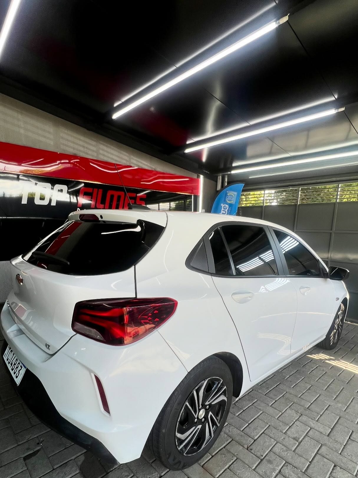 Chevrolet Onix branco com película aplicada na unidade da Top Films em Campo Bom
