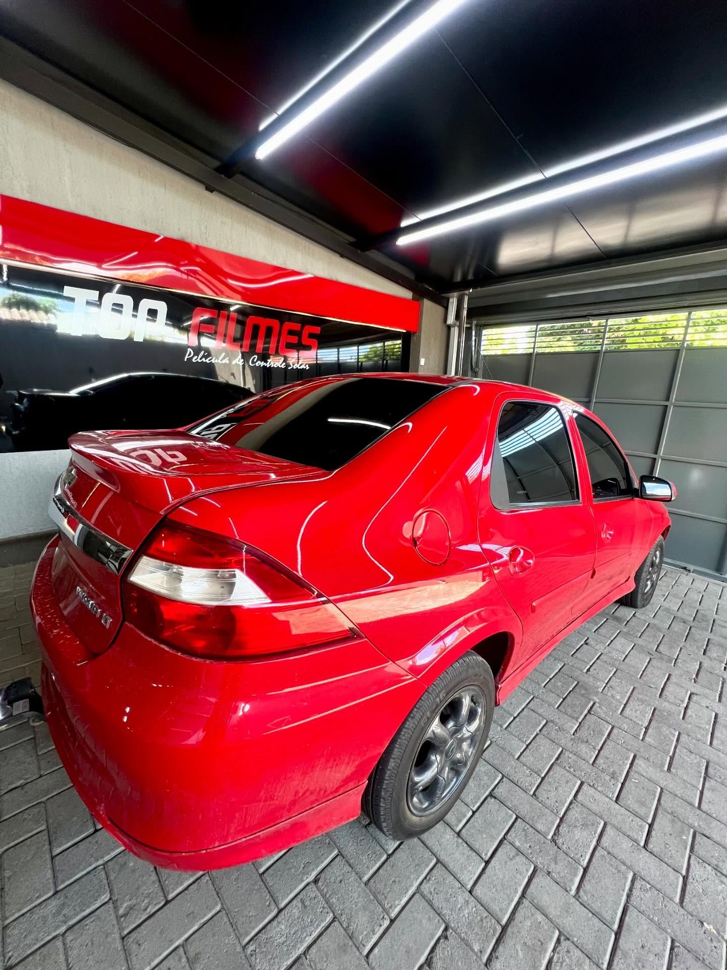Sedan vermelho com película escura nos vidros